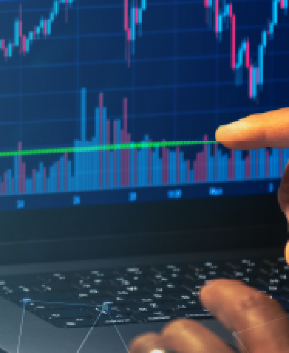 Profissional do mercado financeiro mostrando gráficos no computador.
